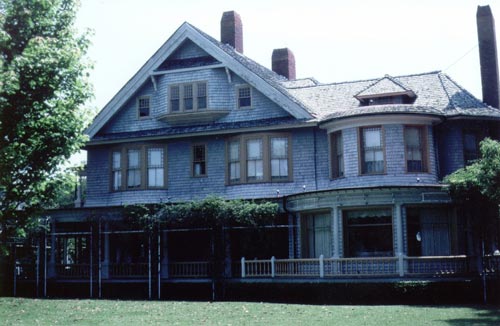 Image of a house with a grass lawn and adjacent trees.
